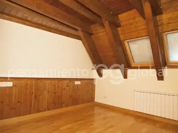 Una de las dos habitaciones del segundo piso con techo con vigas y piso de madera.