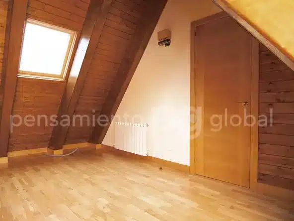 Dormitorio en el piso superior con vigas en el techo y piso de madera.