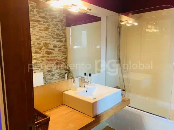 Cuarto de baño moderno con espejo grande y mampara de cristal al lado de la bañera.