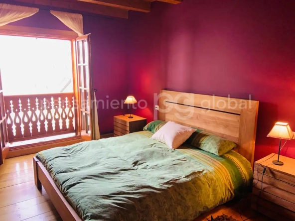 Dormitorio doble con puerta ventana y vigas de madera en el techo.