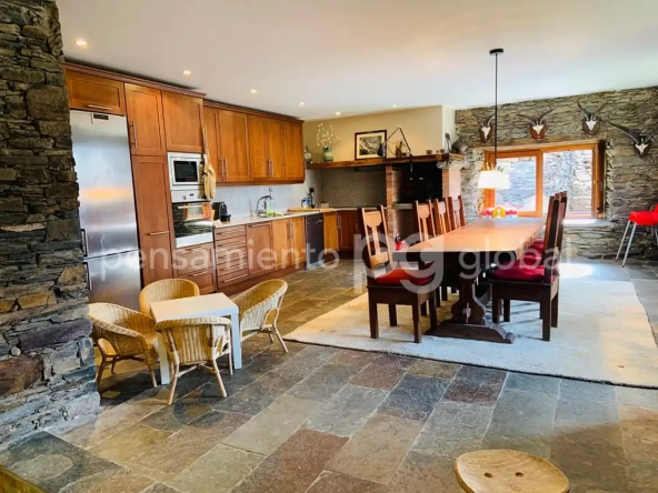Sala y comedor con cocina abierta, una gran nevera de acero inoxidable y una mesa de comedor para ocho a diez personas.