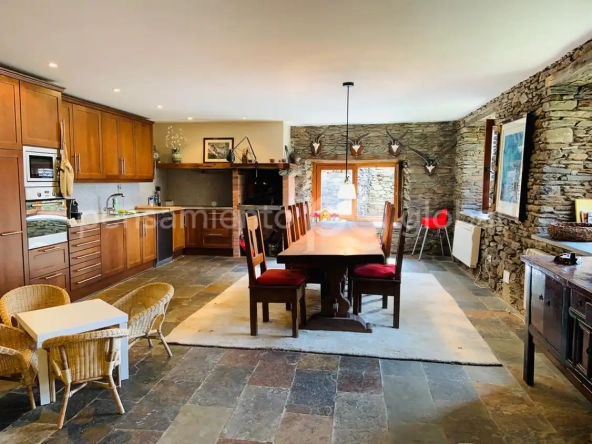 Salón principal con cocina abierta, gran frigorífico de acero inoxidable y mesa de comedor para ocho o diez personas.