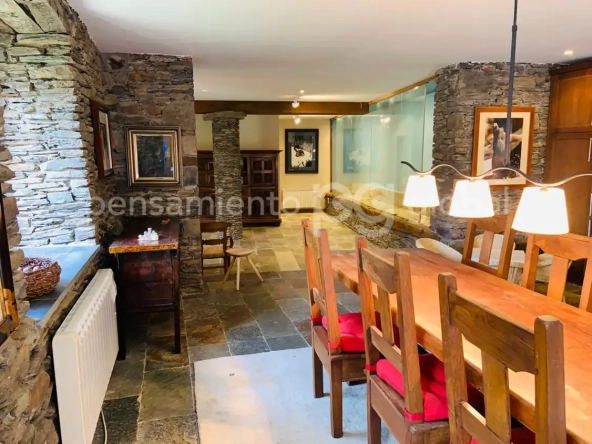 Vista de la sala principal desde el costado de la gran mesa de comedor con un pilar redondo de piedra al final.