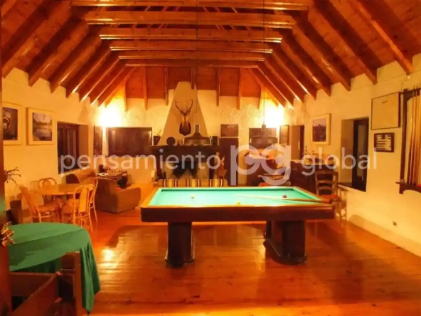 Gran salón con mesa de billar y vigas de madera en el techo.