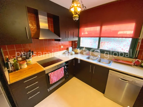 Cocina totalmente equipada con gran ventanal y azulejos rojos.