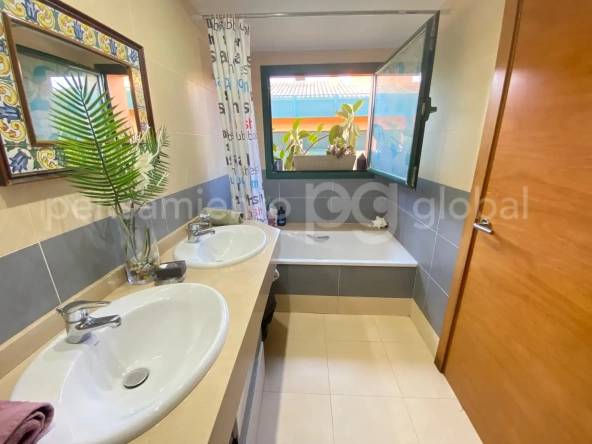 Amplio baño con dos lavabos y ventana.
