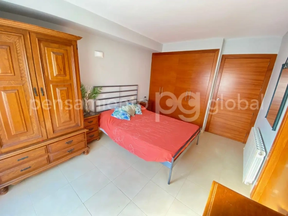 Amplio dormitorio con cama de matrimonio y armario de madera.