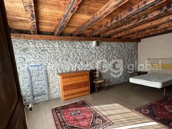 Dormitorio con techo de madera y pared de piedra.