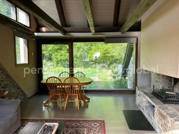 cerca de la chimenea, mesa redonda y cuatro sillas frente a una gran ventana con vista al exterior.