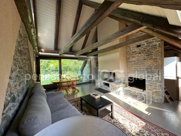 salón con chimenea y paredes de piedra y tejado a dos aguas 