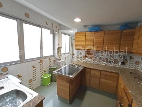 Cocina moderna con armarios de madera y mucha luz natural por las ventanas.