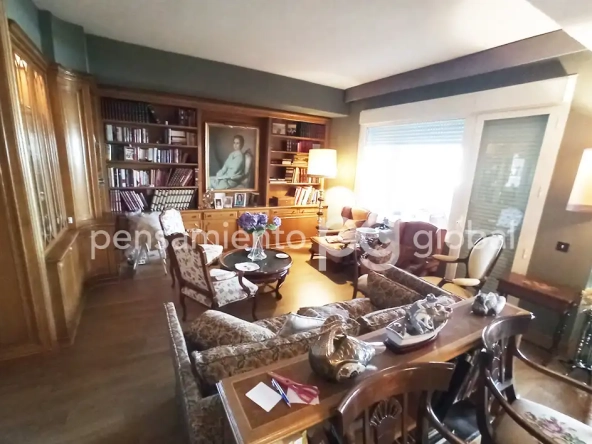Salón con estantería que rodea un retrato, sofá y sillones.