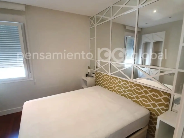 Dormitorio con cama doble y espejos en una pared.