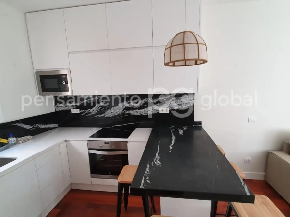 Vista de la encimera de la cocina y el espacio para comer desde el final, mostrando el horno y la encimera.