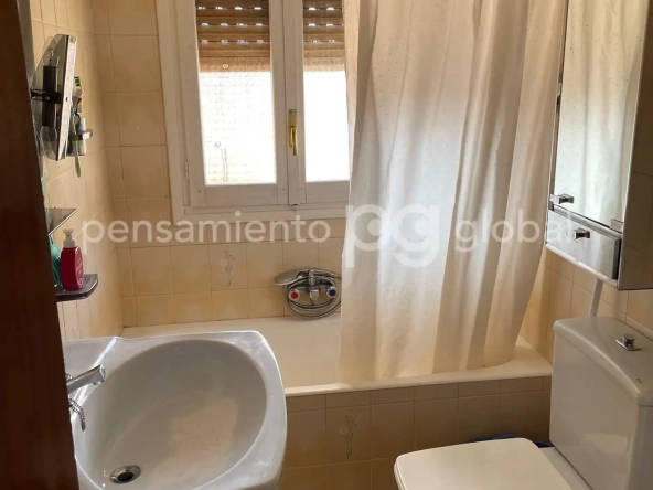Cuarto de baño, bañera, cortina de ducha y ventana.