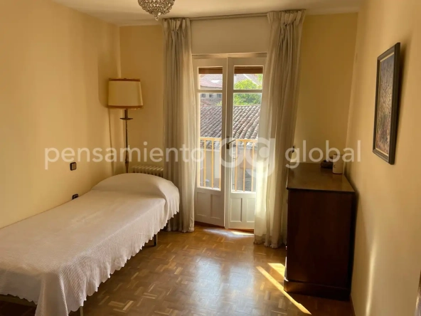 Dormitorio pequeño con una cama individual y balcón.